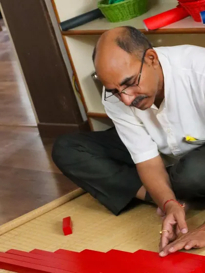 A learner works with the Red Rods, a classic sensorial material. Our training is a process of embodying the learning, not just observing it.