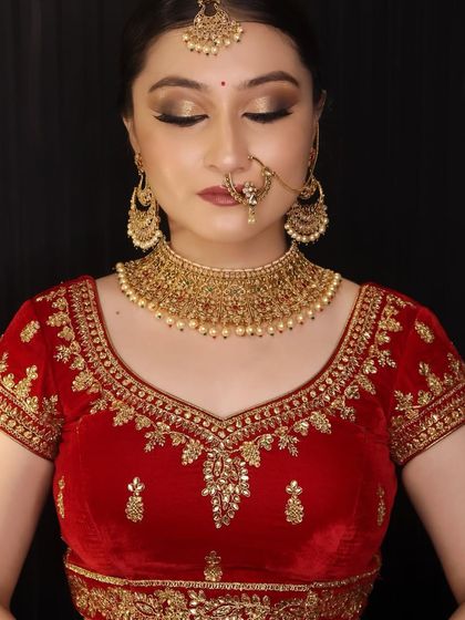 A classic bridal look with golden eyes and a red velvet lehenga, created by a student. This is a testament to their training in traditional bridal makeup techniques.