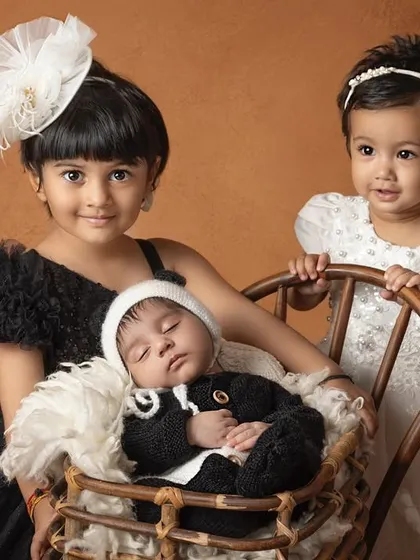The first meeting between siblings is pure magic. Here, two proud big sisters watch over their sleeping newborn brother, creating a beautiful, tender memory of their new family dynamic.