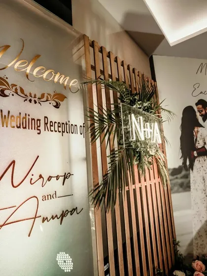 A grand and personalized welcome for a wedding reception. This setup features a large welcome sign with the couple's names, their monogram, and a beautiful pre-wedding photo.