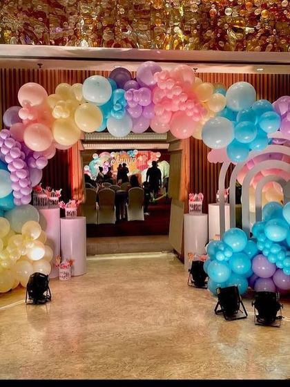 The full entrance decoration for the Peppa Pig party, with a multi-colored balloon arch and character props.