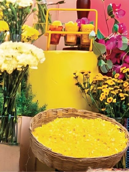 A simple woven basket filled with golden flower petals becomes a beautiful decor element. It's these small, thoughtful touches that add to the vibrant and floral-rich atmosphere of a Mehendi or Haldi ceremony.