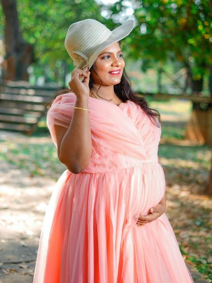 A chic and sunny outdoor portrait. The straw hat and soft pink gown give this solo maternity photo a relaxed, summery feel.