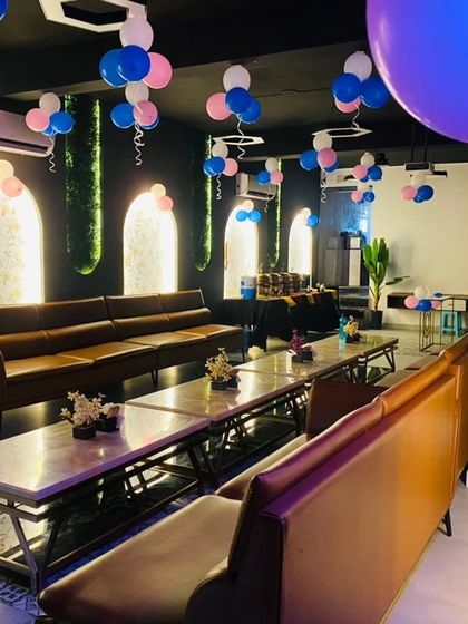 A simple yet festive decoration in a cafe, with pink and blue balloons hanging from the ceiling to add a celebratory touch.