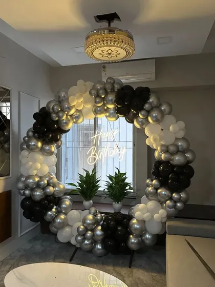 A modern and minimalist balloon ring in black, white, and silver, with two small plants in the center for a unique touch.