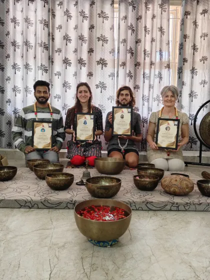 Four graduates proudly display their sound healing certifications, ready to bring this practice to others.