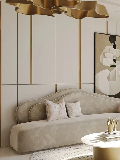 The dramatic gold chandelier acts as a piece of art, floating above the serene, cream-toned living space. The organic shape of the sofa and the abstract art on the wall contribute to a room that feels both sculptural and harmonious.