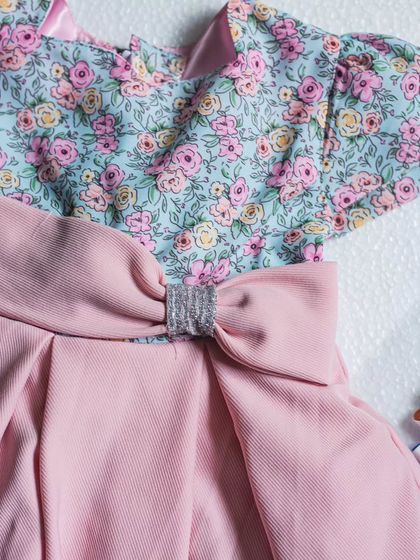 The combination of a soft floral print and a solid pink skirt is always a winner. Here, you can see the detail of the silver-buckled bow that cinches the waist.