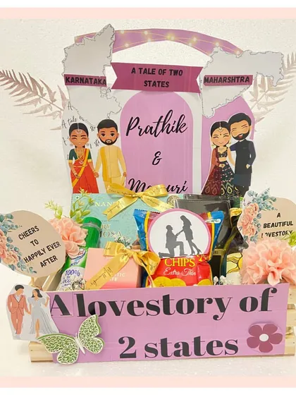 Celebrating a beautiful cross-cultural love story with our 'Tale of 2 States' hamper. This gift features custom caricatures of the couple in their traditional attire from Karnataka and Maharashtra, telling their story through every detail.