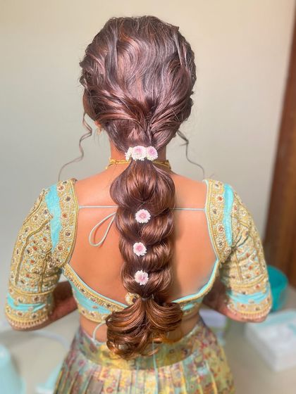 This is a double pull-through braid, a modern style that creates incredible volume and texture. I've adorned it with small, delicate flowers for a soft and romantic finish, perfect for a sangeet or reception.