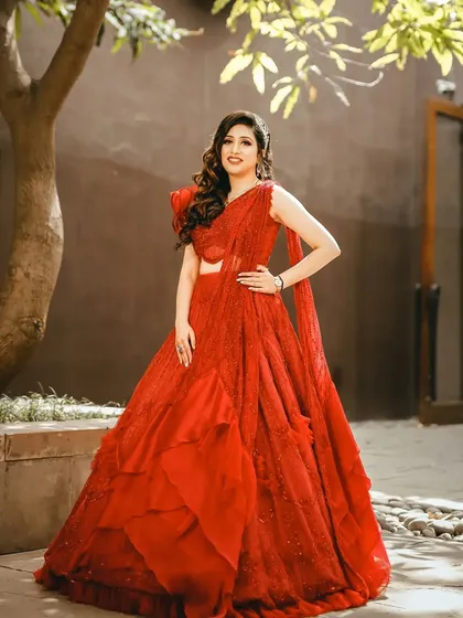 A full-length shot of the bride in her stunning red gown. The makeup is subtle yet glamorous, perfect for a modern bride.