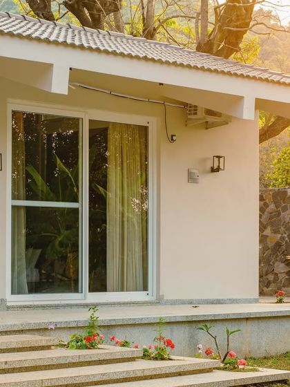 A detail of the Amberle farmhouse, showing the simple material palette of plaster, stone, and glass. The design is intentionally understated to keep the focus on the beautiful, sun-drenched natural surroundings.
