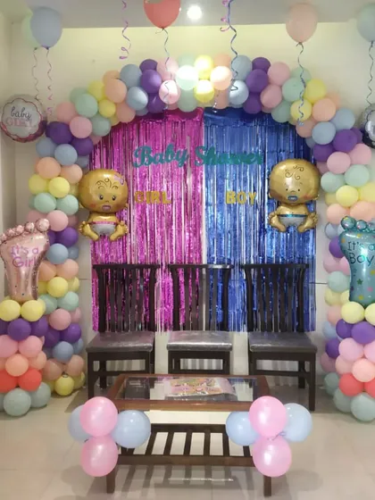 A closer view of the pastel baby shower setup, showing the foil baby balloons and the split pink and blue foil curtain.