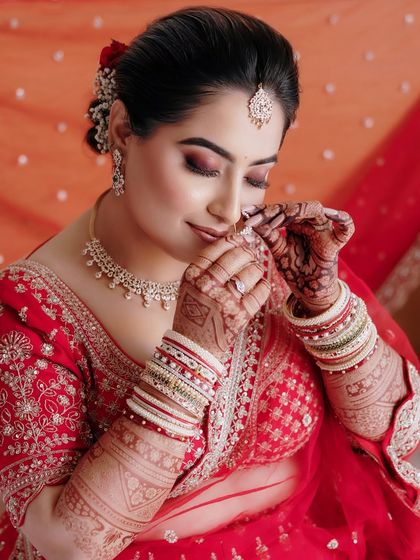 The final touches. This shot captures the intricate details of Sakshi's look, from her henna-adorned hands to her perfectly applied makeup.