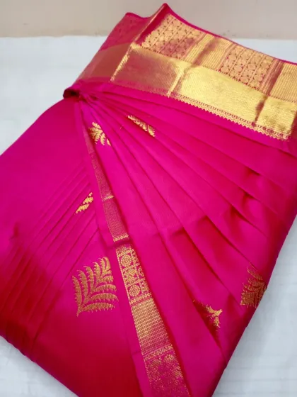 A vibrant pink silk saree, pleated and ready for a special occasion. The gold zari work stands out beautifully against the crisp folds.