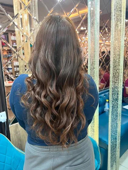 A rich, warm-toned balayage on long hair, styled into beautiful, flowing curls. This look is both glamorous and timeless.