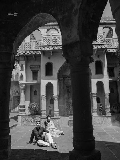 A timeless black and white photograph capturing the couple in a quiet moment within a pillared corridor. This style adds a classic, artistic feel to your pre-wedding album.
