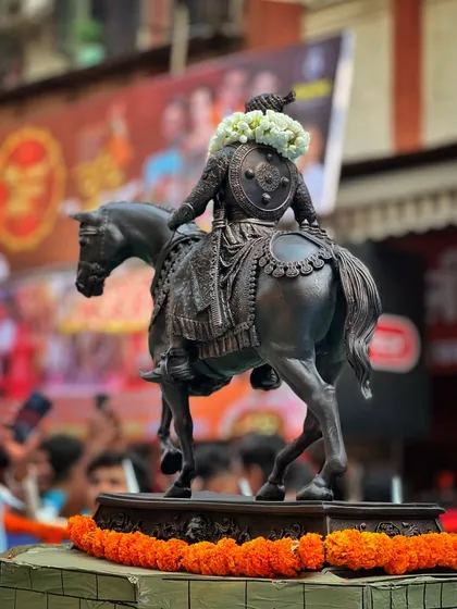 A detailed shot of a statue of Shivaji Maharaj on horseback, adorned with flowers. I focus on the artistry and craftsmanship that is part of our cultural expression.