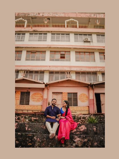 A couple sits on the ghats of Rishikesh, their colorful traditional attire standing out against the architecture.
