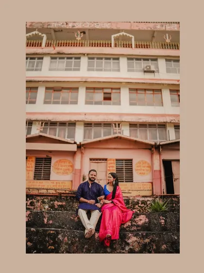 A couple sits on the ghats of Rishikesh, their colorful traditional attire standing out against the architecture.