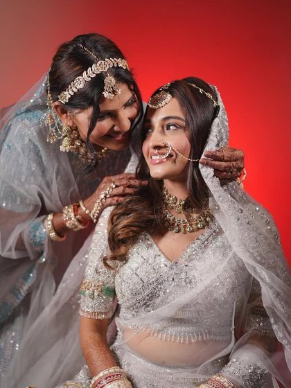A beautiful moment between a bride and her mother. The bride's soft, ethereal makeup in her white lehenga is a perfect example of modern bridal elegance.