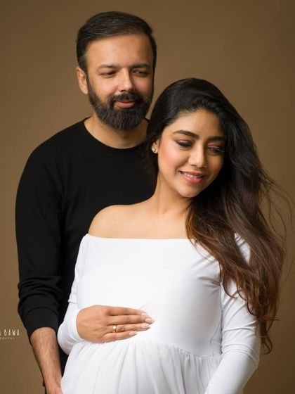 A quiet, intimate moment between an expecting couple. The soft lighting and their gentle interaction create a romantic and timeless portrait.