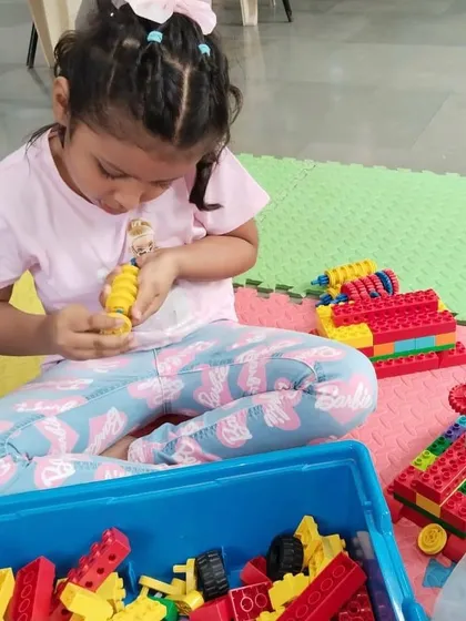 A young student concentrates on her LEGO creation. My classes provide a playful environment where kids can explore their imagination while developing important fine motor skills.