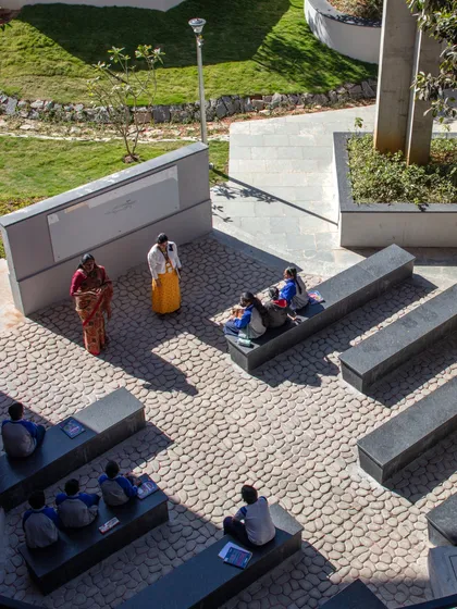 An outdoor classroom at Euro School, Bannerghatta, where learning happens on stone benches amidst nature. We design these spaces to ground education in the real world, using natural textures and open air to stimulate the senses.