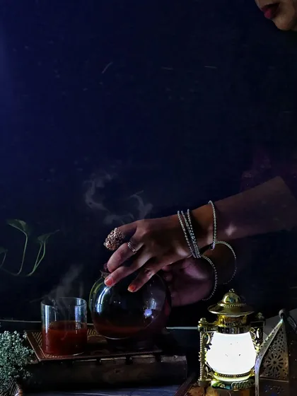 A dark and atmospheric shot of hands pouring tea, with an antique lantern providing a warm glow. This style of photography is great for creating a specific mood for a brand or story.