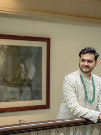 A classic portrait of the groom, looking sharp and sophisticated in his white sherwani and emerald necklace.