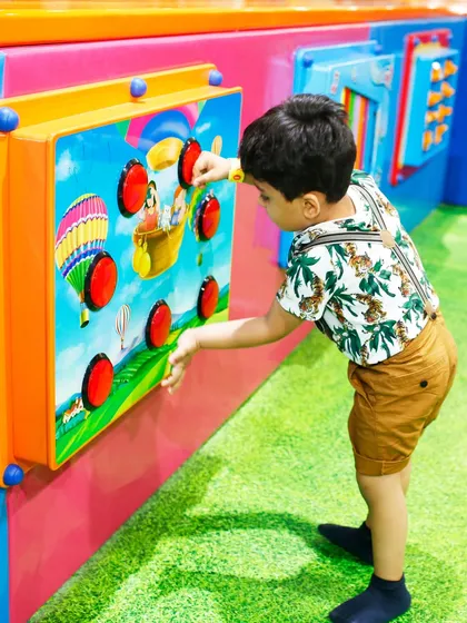 A young child engages with a sensory wall panel in the My Burrow area. These activities are designed to stimulate cognitive development through touch and play.