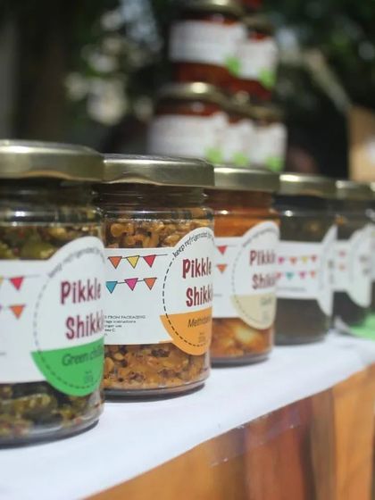 My pickles lined up at a market stall. You can see the variety, from Green Chilli to Methi Dana, each with its own distinct label and flavour.