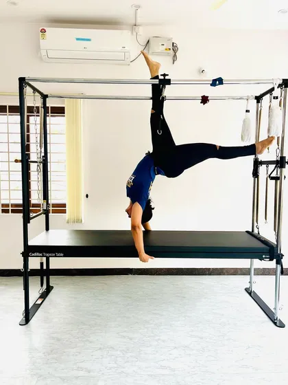 A client showing amazing progress with an inverted handstand pose on the Cadillac, a true test of balance and strength.