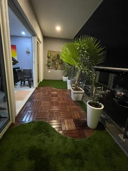 This urban balcony is now a chic, modern retreat. We combined stylish wood-composite deck tiles with patches of artificial turf and elegant planters to create a beautiful and low-maintenance outdoor space.