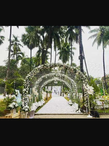 The entrance to a stunning "White Wedding" by the beach. The long floral tunnel, made entirely of white flowers, creates a dramatic and elegant walkway leading to the ceremony.