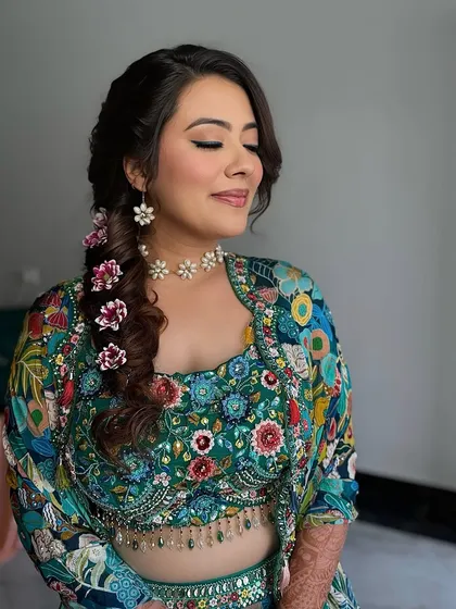 A beautiful braided hairstyle adorned with flowers for Akansha's Mehendi. This look is both practical and stunning, keeping the hair off the face while looking incredibly festive.