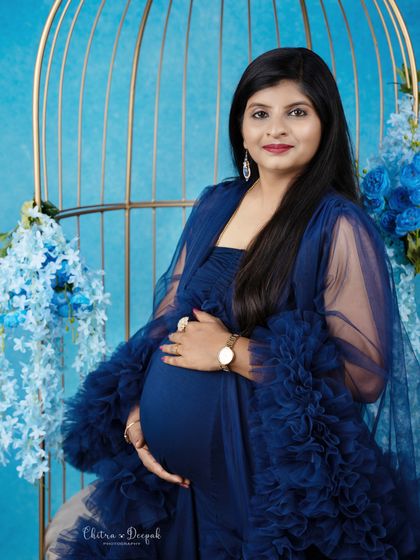 A close-up portrait in royal blue. The golden birdcage and matching blue flowers create a cohesive and luxurious look.