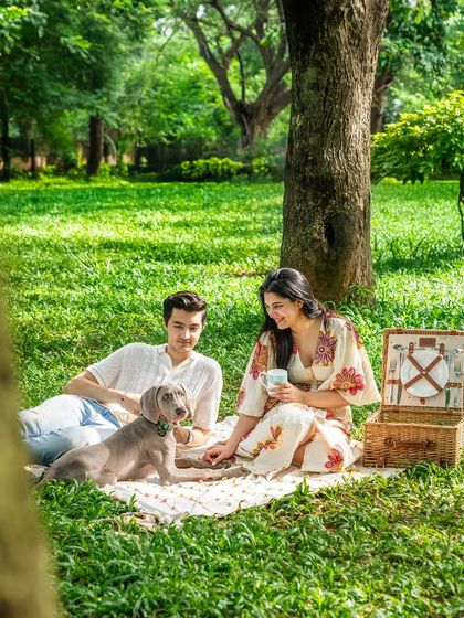 A beautiful, fully edited photo of a couple enjoying a picnic with their Weimaraner puppy. This is the "after" shot, showcasing a perfect, dreamy outdoor moment.