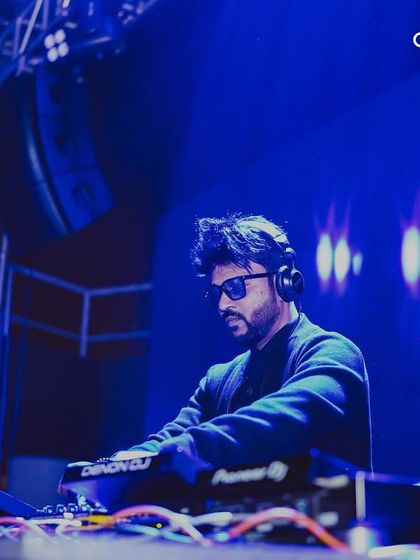 A DJ at the console, surrounded by the vibrant lights of a New Year's Eve party. The production quality is a key focus for all my signature events.