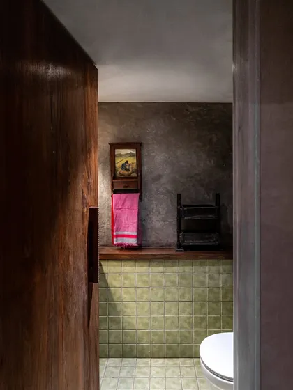 Even the washroom at the Eka store continues the design narrative. We used earthy green tiles, an exposed concrete finish, and repurposed wood for the door handle and towel rack to create a space that feels raw, natural, and familiar.