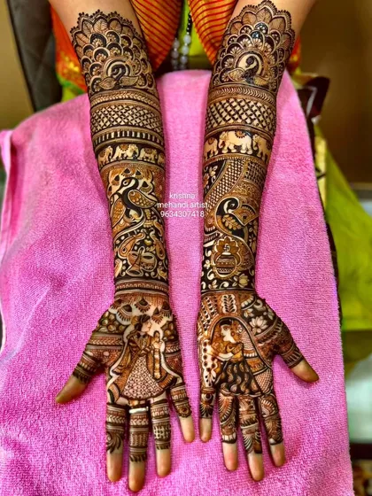 A very intricate design covering the full arms. It includes bride and groom figures, peacocks, elephants, and kalash motifs, all done with fine lines.