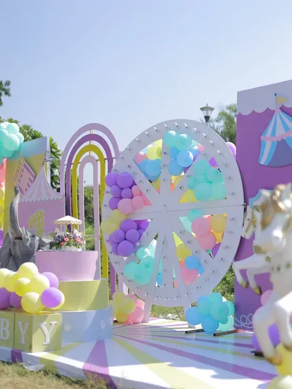 A wide shot of the outdoor pastel carnival stage. The setup includes a large Ferris wheel, carousel horses, and rainbow arches, creating a complete wonderland on the lawn.
