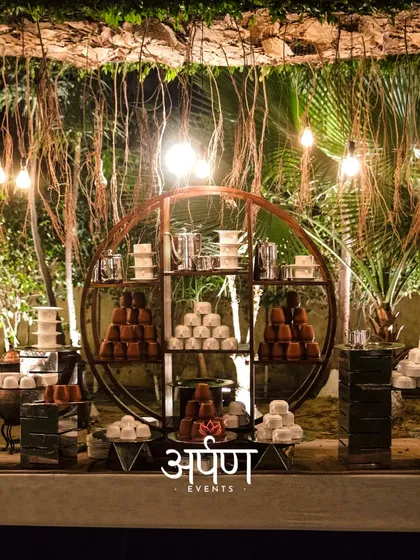 A stunning dessert and beverage station with rustic-chic decor, featuring an array of traditional Indian sweets and drinks.