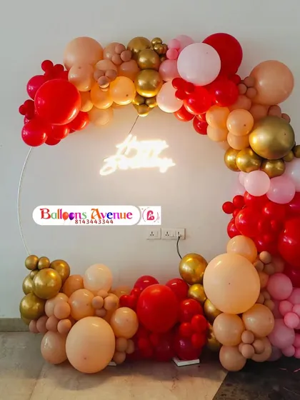 A close-up of the red and gold balloon arrangement with the 'Happy Birthday' neon sign glowing in the center.