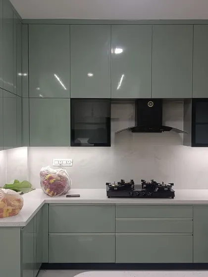 A look at a recently completed modular kitchen featuring a serene sage green palette with a high-gloss finish. This design showcases our factory-finished precision, complete with handleless cabinets, integrated appliances, and under-cabinet lighting for a clean, functional, and modern culinary workspace.