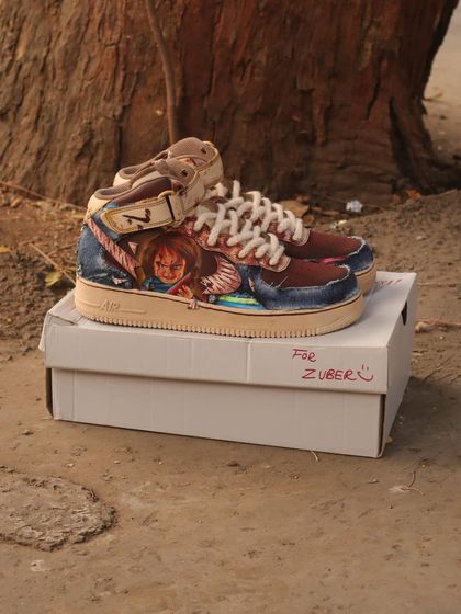A full view of the Chucky-themed sneakers. The coffee-dyed base gives the shoes a grimy, aged look that perfectly fits the horror theme.