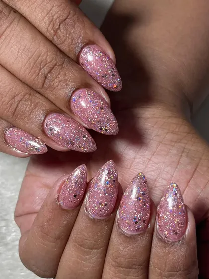 A different angle of the pink glitter nail extensions for a bridesmaid. The stiletto shape is modern and chic, and the glitter finish is perfect for celebrating a special day.