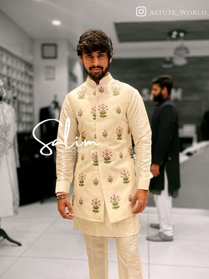 A client wearing an off-white kurta set with a matching Nehru jacket that features delicate floral embroidery. A perfect choice for a sophisticated daytime event.