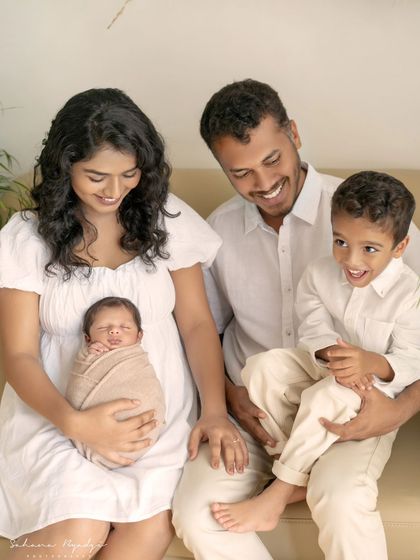 A happy family of four, with the older brother looking so proud of his new sibling.