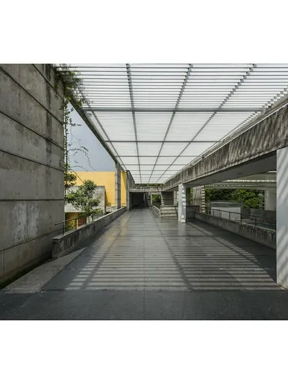 The main circulation spine at the IIM Bangalore Sports Center. The interplay of light and shadow created by the pergola is a key element, transforming a simple walkway into an experiential journey that connects various parts of the facility.